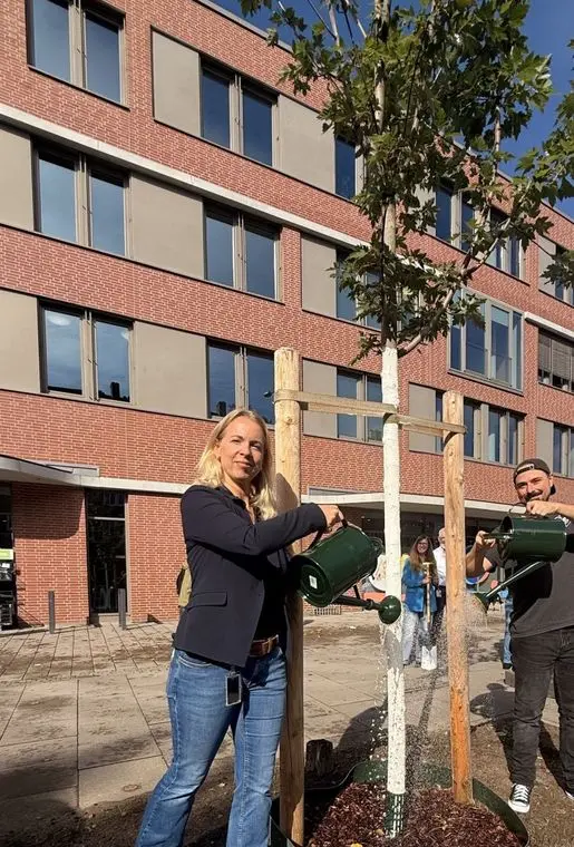 Katja Groß pflanzt einen Baum vorm Head Office in Hamburg