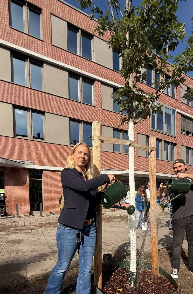 Katja Groß pflanzt einen Baum vorm Head Office in Hamburg